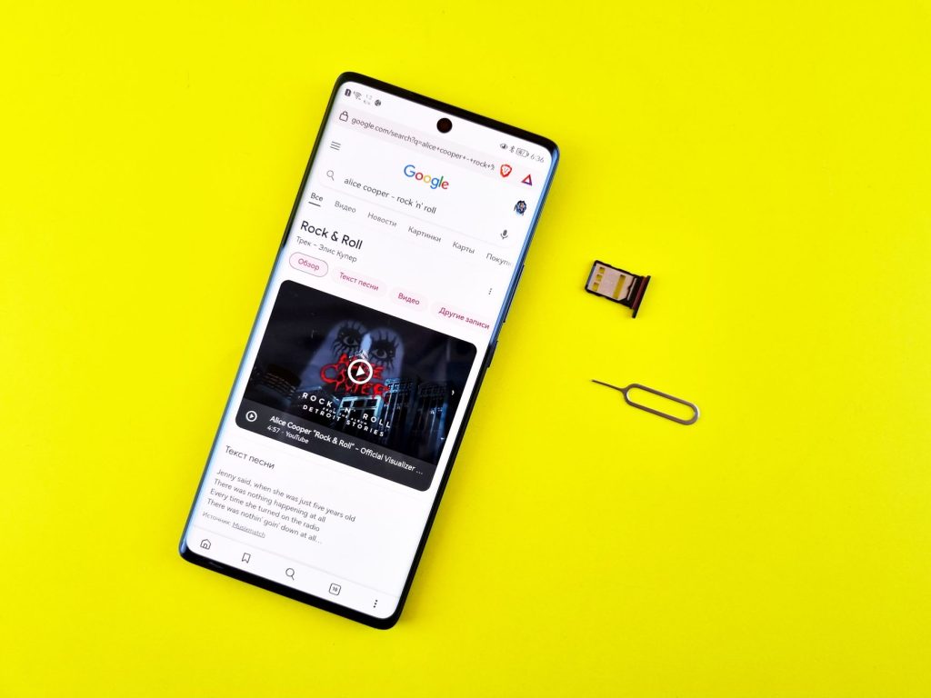 Smartfon z wyszukiwarką Google, kartą SIM i szpilką do jej wyjmowania